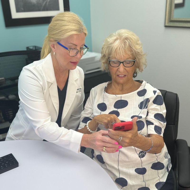 Dr. Diesman leaning in to help a seated patient with something on her phone